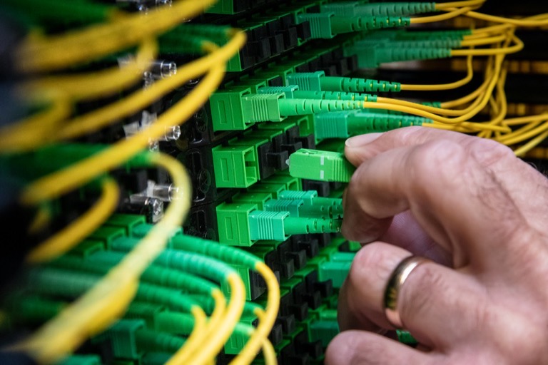 Technician patching single-mode fibre connectors on a distribution frame – fibre termination and patching Brisbane